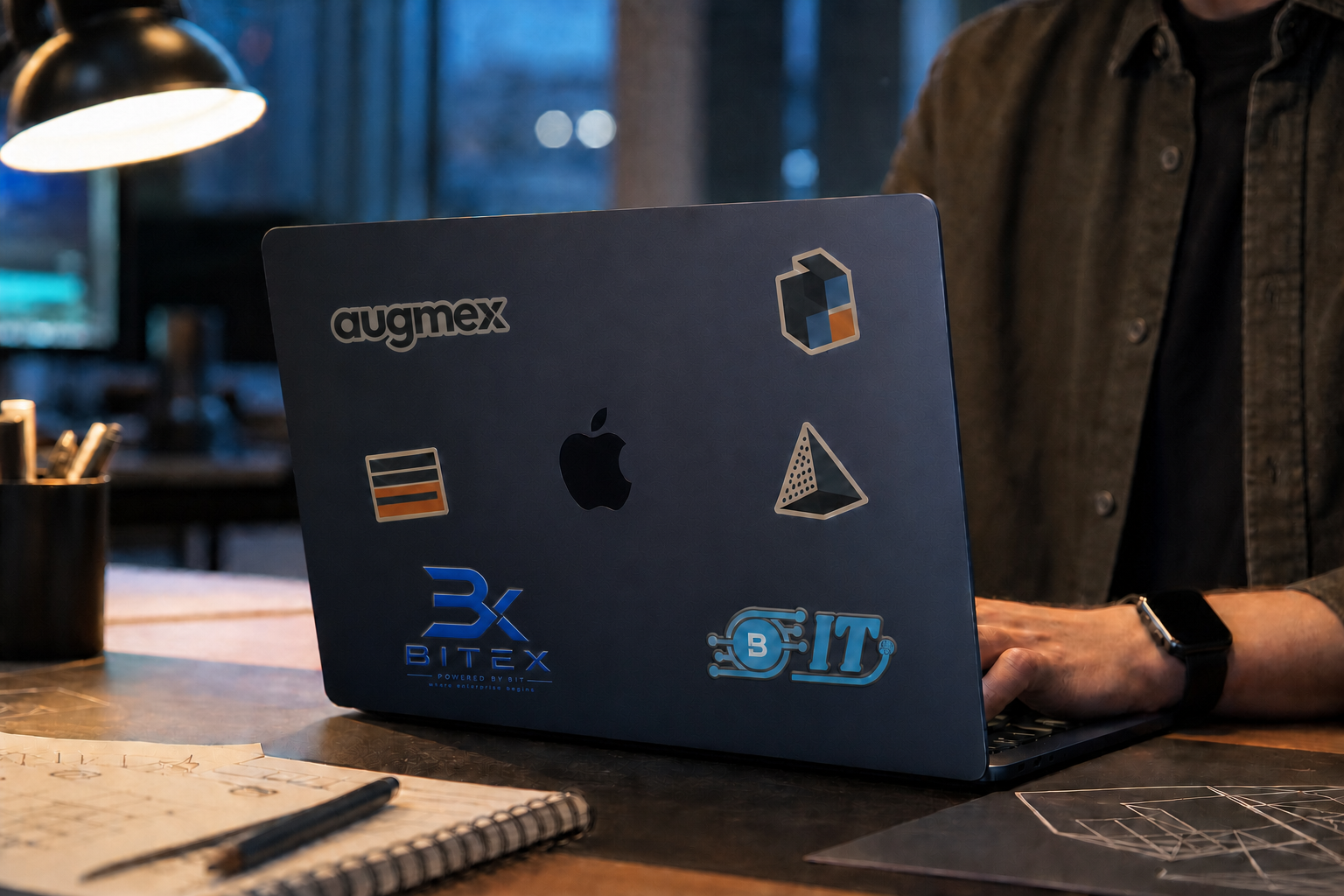 A person working on a branded Midnight MacBook at a design desk