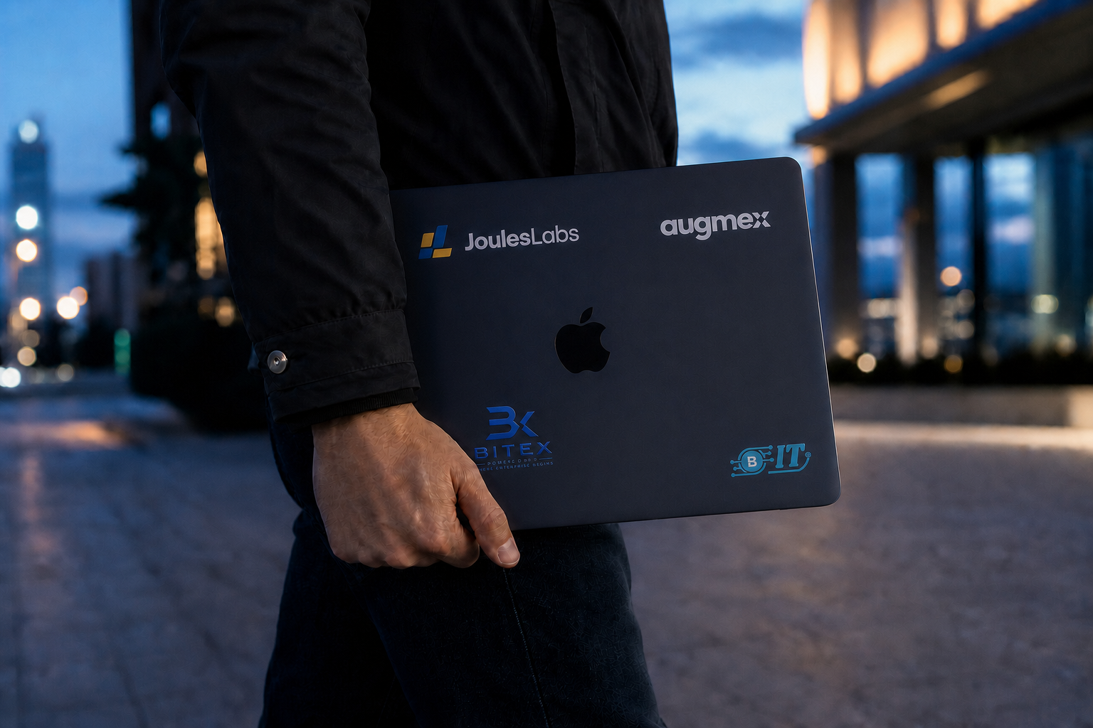 A Midnight MacBook with brand stickers being carried through a city
